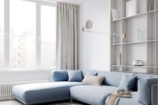11 a beautiful minimalist living room with a blue sectional, grey curtains, a low round table and cool built-in shelves