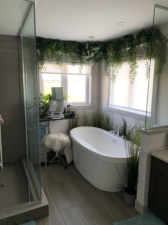 a cozy little bathroom with lots of plants, faux and real ones and with windows for natural light