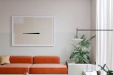 12 a beautiful minimalist living room with a pale grey color block wall, an orange sofa, a jute rug and a leather chair