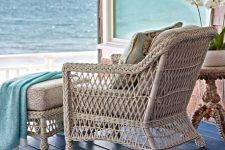 15 a coastal porch with a rattan chair and an ottoman, with blue textiles and a gorgeous view of the sea is amazing