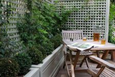 15 a small and cozy backyard with a deck, a simple wooden outdoor furniture set, potted greenery and climbing plants is very cozy