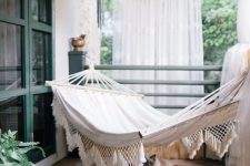 17 a boho porch with curtains, string lights, a hammock, a boho rug and potted plants is a very cool idea for relaxing outdoors
