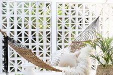 21 a dreamy outdoor space with a white pergola, a woven hammock with pillows, jute accessories and potted greenery is chic and beautiful