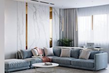 21 a minimalist living room with a blue sectional, hidden storage units with marble panels and neutral textiles all over