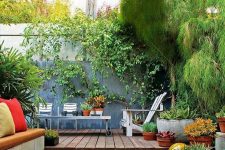23 a small backyard with pebbles and a sitting zone with a built-in bench, lots of potted plants, a living wall and modern garden furniture