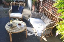25 a lovely terrace with a red brick wall, rattan furniture, printed pillows and lots of potted greenery and blooms around