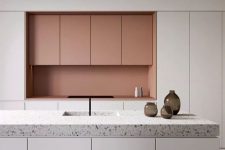 27 a minimalist kitchen with sleek white cabinetry, a terrazzo countertop and a peachy pink backsplash and upper cabinets