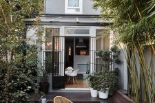 27 a small minimalist backyard with a dark stained deck and a tiled floor, with growing bamboo and plants and chic woven chairs and a table