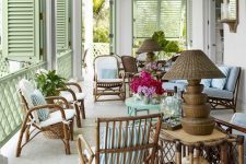 28 a stylish veranda with rattan chairs, a blue table and a sofa, a rattan table and a wicker lamp plus green shutters on the windows
