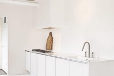 30 an airy white minimalist kitchen with sleek cabinets and a white hood that merges with the wall and is almost invisible