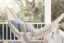 31 a relaxed coastal porch with a hammock with tassels and printed pillows, a striped pouf and candle lanterns in the corner