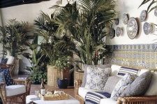 32 a tropical terrace with rattan furniture, printed pillows and blankets, potted plants, mosaic tiles, a printed rug and some lamps