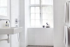a Scandi bathroom with white square tiles and a black and white terrazzo floor, white appliances and a large window