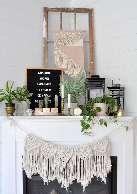 a boho summer mantel with macrame, potted greenery, candles in candleholders, candle lanterns and brass and gold touches