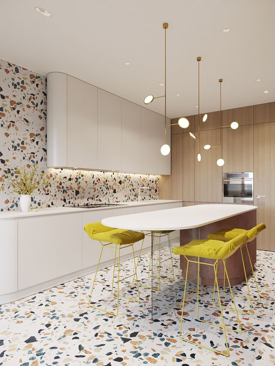 a bright and fun kitchen with a colorful terrazzo floor and wall, white curved cabinets, a curved kitchen island and mustard stools