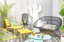 a bright summer terrace with a printed rug, turquoise, yellow and black woven furniture, potted plants and printed pillows is welcoming