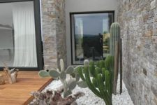 a chic modern front yard with white pebbles and grass, with cacti and driftwood looks bold and chic and paired with a desk is amazing