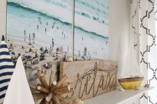 a coastal mantel with a vacation photo as a centerpiece, a wooden sign and wooden decor, a couple of boats and seashells