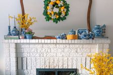 a colorful summer mantel with a lemon wreath, a yellow flower arrangement, chinoiserie, bright blue textiles and yellow branches
