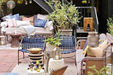 a colorful summer terrace with a tiled floor, rattan and wooden furniture, colorful printed pillows, blue accessories for a coastal feel