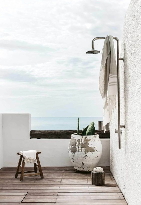 a contemporary Mediterranean shower space with a sea view, a wooden deck, a large shabby chic planter, a stool and a tree stump