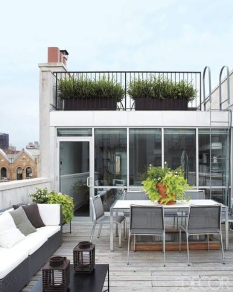 a contemporary rooftop terrace with a wooden deck, a large sofa, a dining set with metal chairs and potted greenery is cool and chic