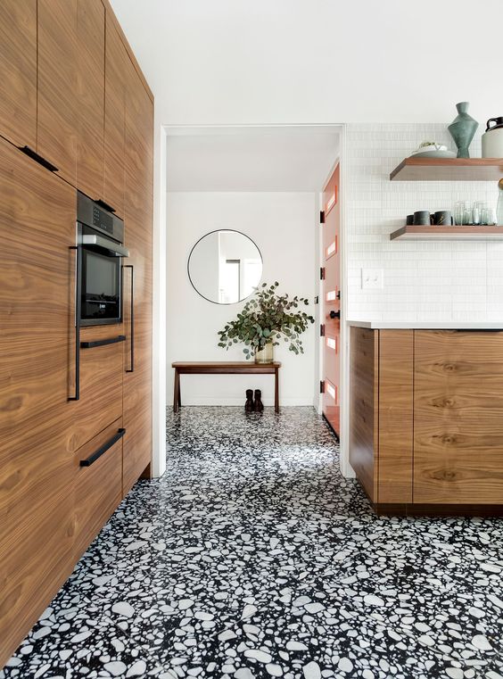a contemporary space with white walls, a black and white terrazzo floor, chic stained cabinets and open shelves is a lovely room