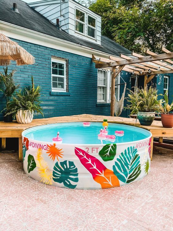 a cool stock tank pool with colorful painted elements for decor and colorful floats is a lovely idea to have in your summer backyard