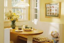 a cozy yellow dining space with yellow walls and white paneling, a folding table and built-in benches, a pendant lamp and a bold artwork