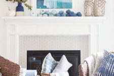 a creative coastal fall mantel with blue pumpkins featuring an ombre effect, with a color  block vase with fall leaves and candle lanterns in woven rope