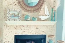 a gorgeous coastal mantel with a buoy, an aqua faux seashell, aqua vases with pampas grass, a boat and a family pic plus aqua candles around