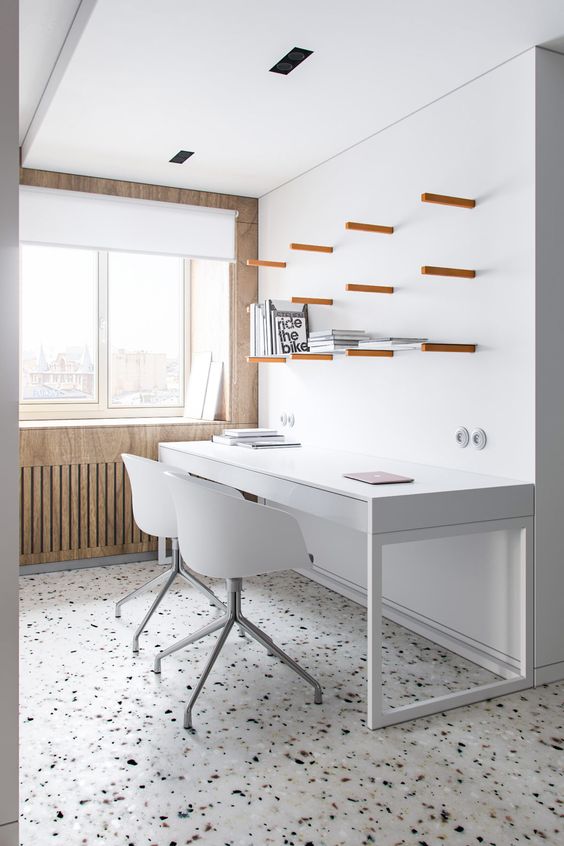 a lovely contemporary home office with white walls and a plywood one, a white and black terrazzo floor and chic white furniture