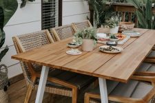 a lovely outdoor dining space with a simple table and woven chairs, with potted plants and a greenery wreath is welcoming