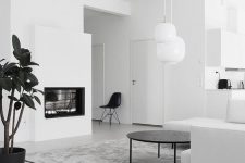 a minimalist white living room with a built-in fireplace, a white sofa and a black round coffee table, pendant lamps and black touches