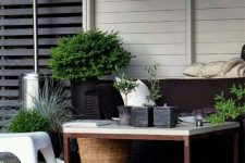 a modern and lively summer terrace with a low table and chairs, a pendant woven lammp, potted greenery and a basket