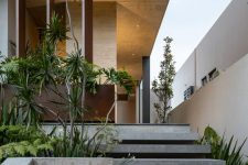 a modern front yard done with concrete for a sleek feel, with greenery and trees that refresh the sleek and minimal look of the yard