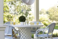 a neutral coastal dining space with a chic round table and white and blue rattan chairs plus white woven pendant lamps