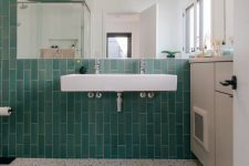 a pretty bright bathroom with turquoise skinny tiles and grey and white terrazzo flooring, white appliances and a large mirror