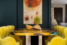 a refined formal dining space with a navy accent wall, lemon yellow chairs, a colorful table and a bold artwork on the wall