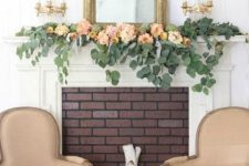 a refined summer mantel with greenery and pastel blooms, with a mirror in a gilded frame and a duo of candleholders is chic