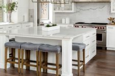a refined white kitchen with chic cabinetry, a large kitchen island, metallic touches and beautiful hardwood floors