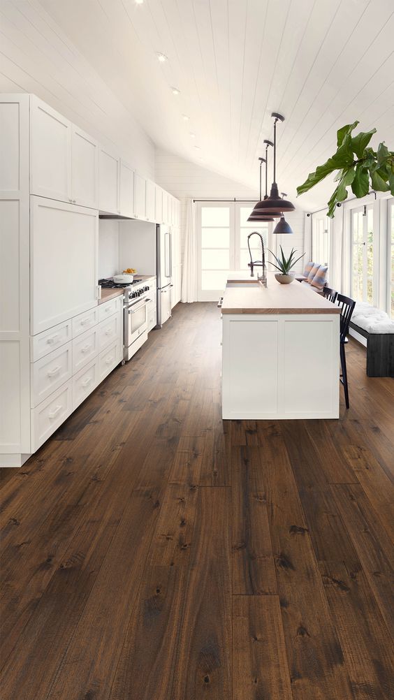 a rich stained hardwood floor contrasts the white shaker style kitchen cabinetry creating a bolder and cooler look