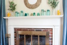 a simple summer mantel with lots of various jars and vases, with eucalyptus in vases, lemons in jars and a mirror in an ornated frame