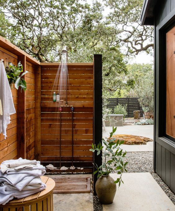 a cute outdoor shower with a wooden mat