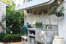a small minimalist concrete kitchen with open storage compartments, a grill and a large sink plus potted herbs is very cool and practical