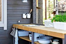 a small rustic Scandinavian outdoor kitchen with a planked floor, a long open shelving unit and pendant lamps is cool