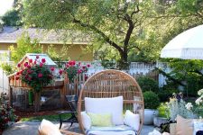 a summer outdoor space with rattan furniture, a striped coffee table, printed textiles and greenery and blooms is welcoming