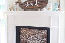 a super cool coastal mantel with starfish, a cloche with one of them, jars and vases, branches and a planked whale