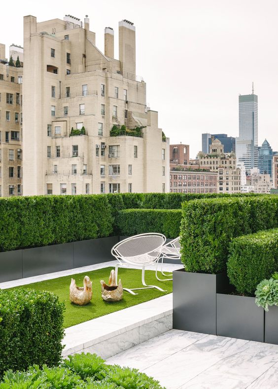 a super elegant and refined contemporary rooftop terrace with greenery walls, a small lawn and a couple of chairs is very inviting