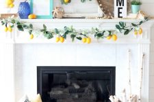 a super fun summer mantel with a greenery and lemon garland, lemons on the wreaths and in a jar, frames and potted plants